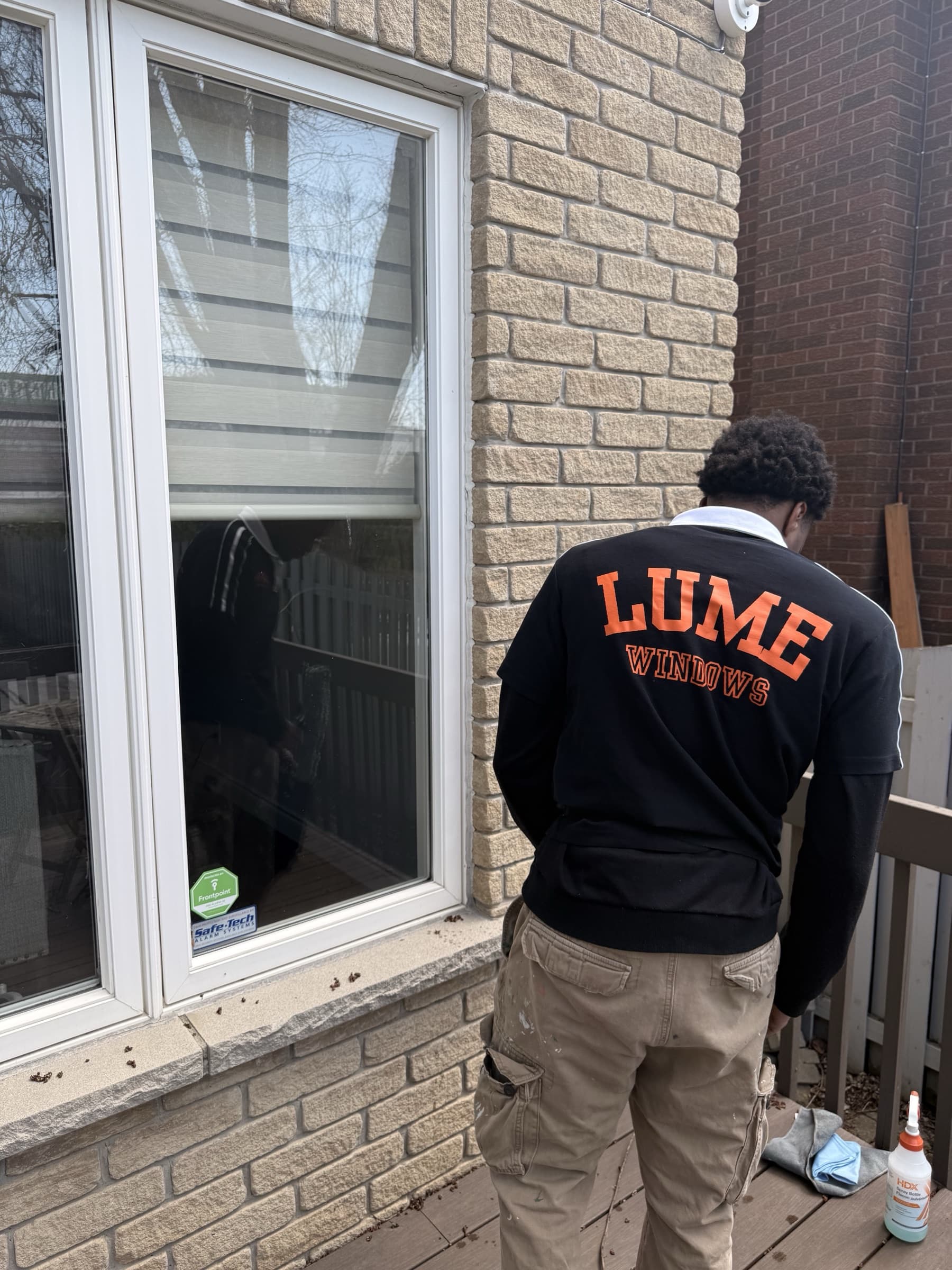 Lume Windows technician cleaning exterior windows on a brick home